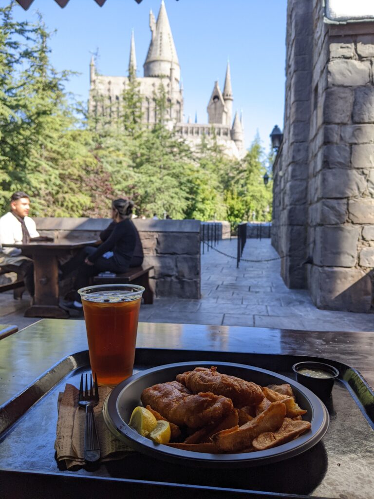 Eating a delicious Three Broomsticks fish and chips meal and Hogs Head beer with a view of the Hogwarts Castle at the Wizarding World in Universal Studios Hollywood